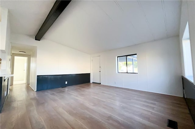 spare room with vaulted ceiling with beams and hardwood / wood-style floors