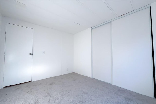 unfurnished bedroom with light colored carpet and a closet