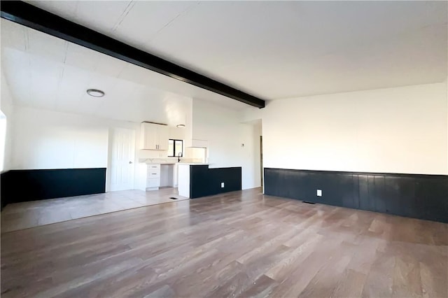 unfurnished living room with lofted ceiling with beams and light hardwood / wood-style flooring