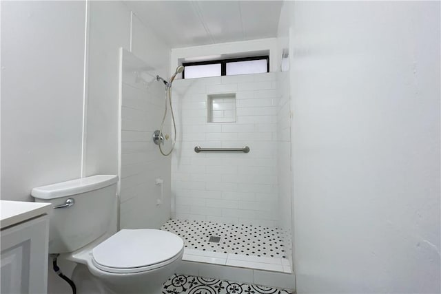 bathroom featuring toilet, vanity, and tiled shower