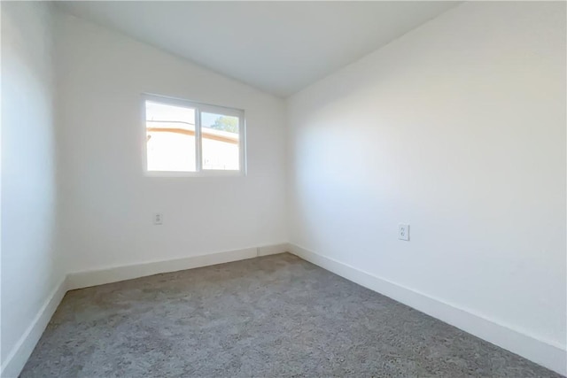 carpeted empty room with vaulted ceiling