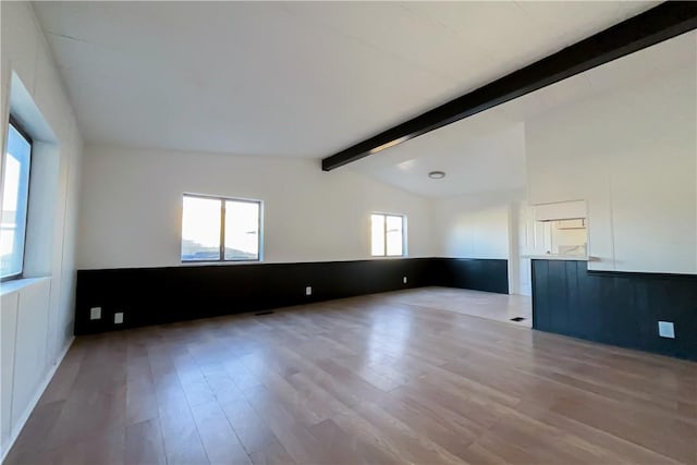 unfurnished room featuring lofted ceiling with beams and light wood-type flooring