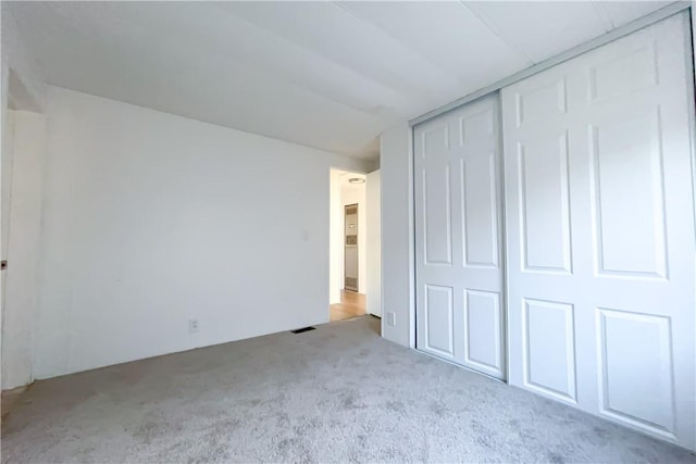 unfurnished bedroom with light colored carpet and a closet