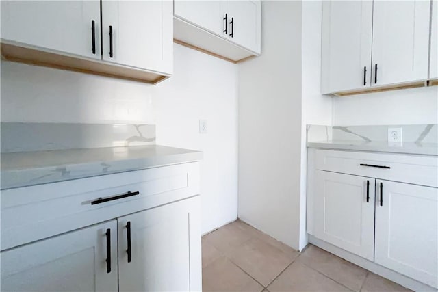 kitchen featuring light tile patterned floors, light stone countertops, and white cabinetry