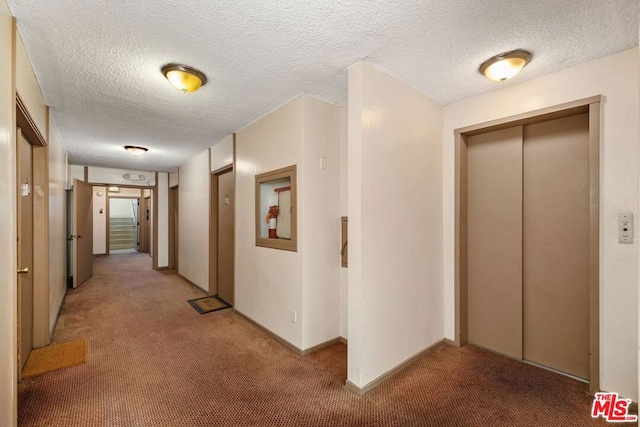 hallway with carpet, a textured ceiling, and elevator