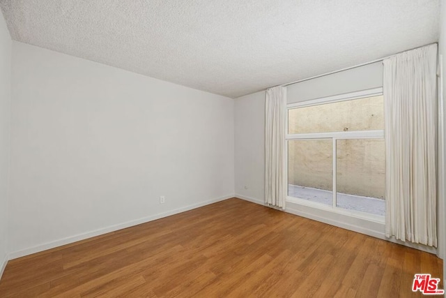 unfurnished room featuring a textured ceiling and hardwood / wood-style floors