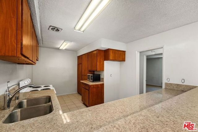 kitchen with white range with electric cooktop, sink, a textured ceiling, and light tile patterned flooring