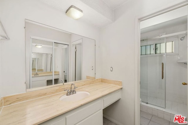 bathroom with a shower with door, a textured ceiling, vanity, and tile patterned flooring