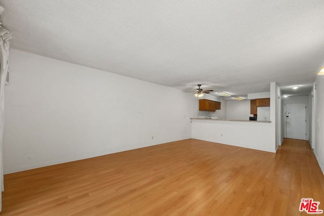 unfurnished living room with a textured ceiling, ceiling fan, and light hardwood / wood-style flooring