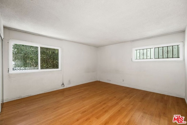 empty room featuring a textured ceiling and light hardwood / wood-style floors