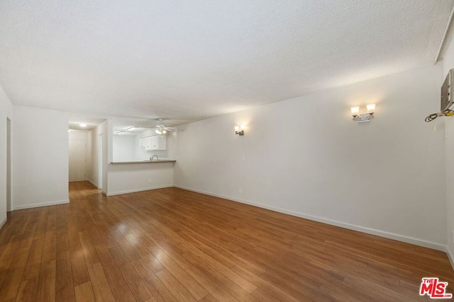 unfurnished living room with a textured ceiling, ceiling fan, and hardwood / wood-style floors