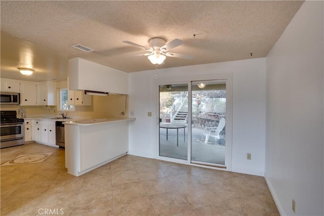 kitchen with white cabinetry, kitchen peninsula, ceiling fan, stainless steel appliances, and a textured ceiling