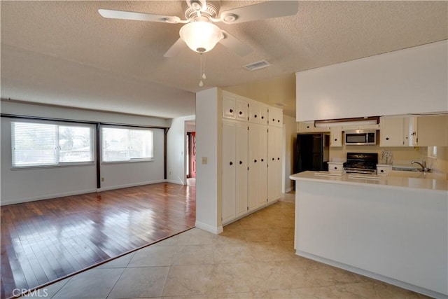 kitchen with ceiling fan, kitchen peninsula, light tile patterned floors, appliances with stainless steel finishes, and white cabinets