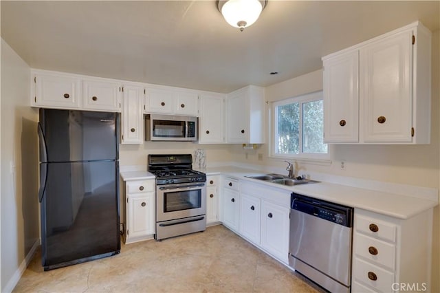 kitchen featuring light tile patterned floors, appliances with stainless steel finishes, white cabinets, and sink