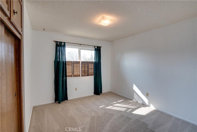 spare room featuring a textured ceiling and light carpet