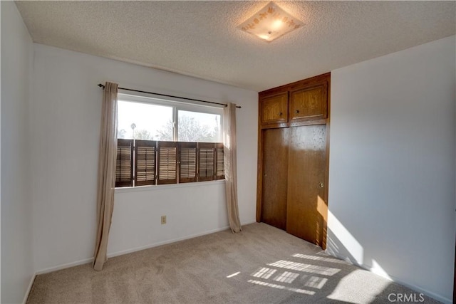 unfurnished bedroom featuring a textured ceiling and light colored carpet