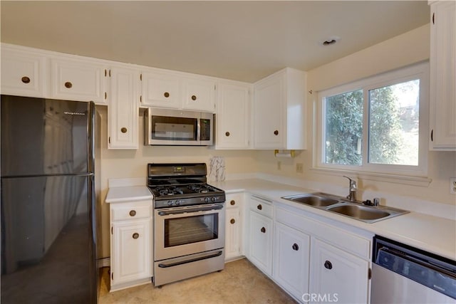 kitchen with appliances with stainless steel finishes, white cabinets, and sink