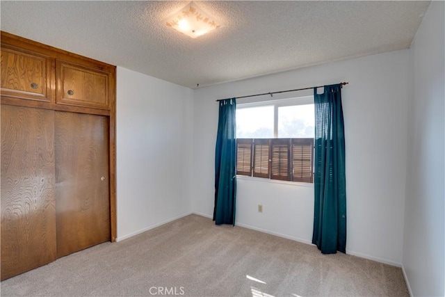 unfurnished bedroom featuring a textured ceiling and light colored carpet