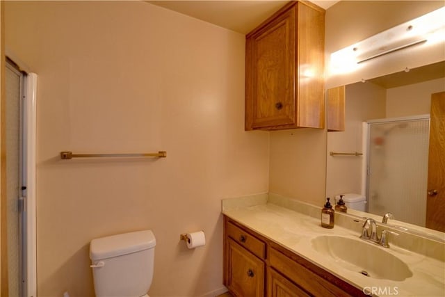 bathroom featuring toilet, a shower with door, and vanity