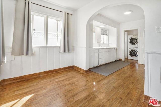 interior space with a healthy amount of sunlight, stacked washer / dryer, sink, and light hardwood / wood-style floors