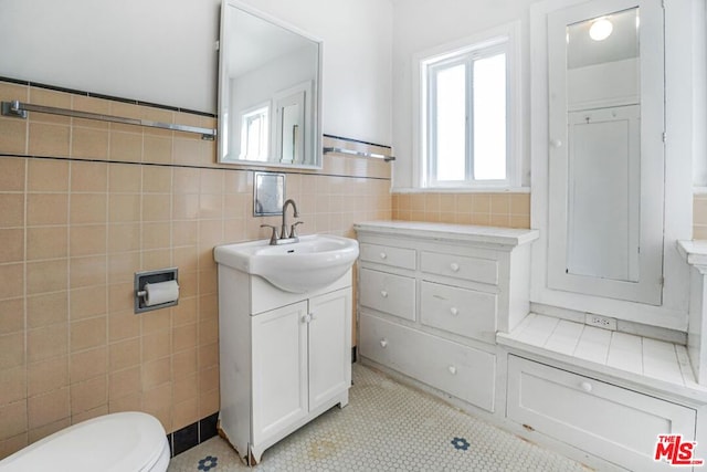 bathroom with vanity, toilet, tile patterned flooring, and tile walls