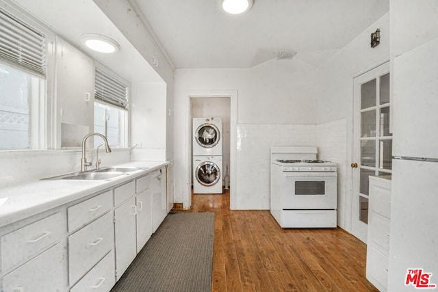 kitchen with sink, white cabinets, stacked washer / drying machine, white appliances, and light hardwood / wood-style flooring