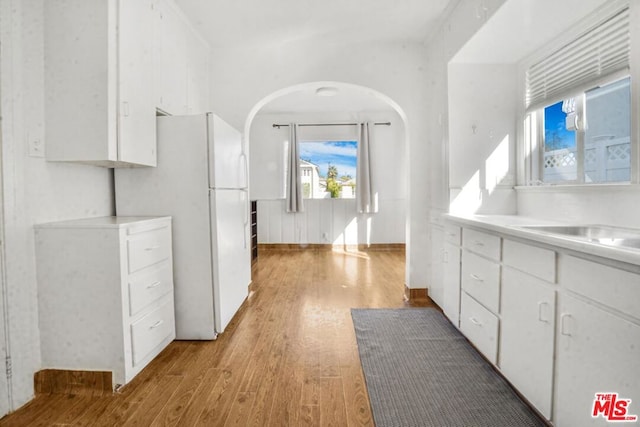 kitchen featuring white cabinetry, white fridge, and light wood-type flooring