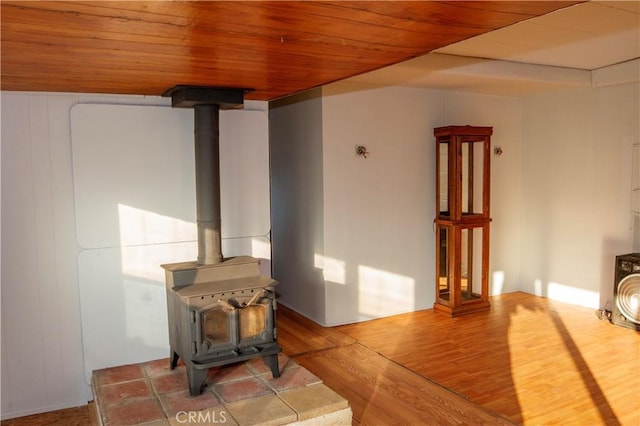 living room featuring wooden ceiling, a wood stove, and wood-type flooring