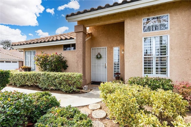 doorway to property featuring a tile roof and stucco siding