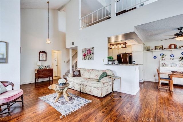 living room with ceiling fan, wood finished floors, stairway, and beamed ceiling
