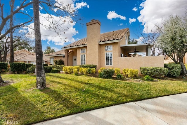 exterior space with a chimney, a tile roof, stucco siding, fence, and a lawn