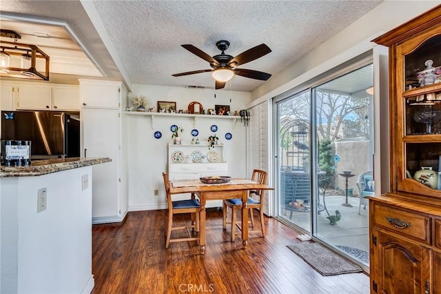 dining space with dark wood finished floors, a textured ceiling, visible vents, and a ceiling fan