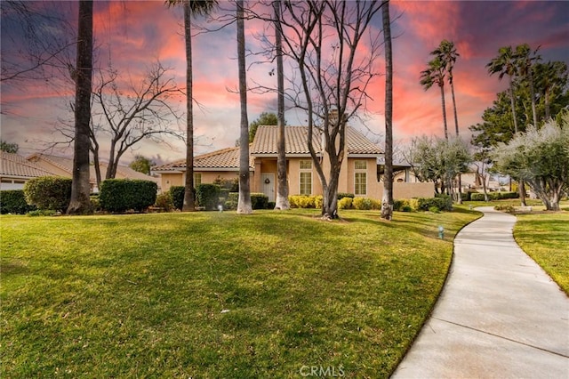 mediterranean / spanish house featuring a front yard, a tiled roof, and stucco siding