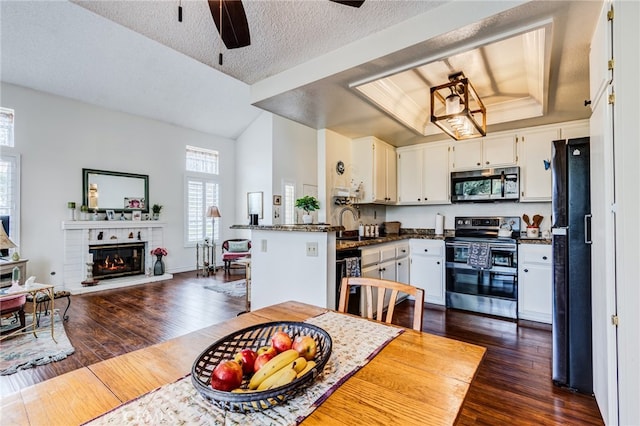 kitchen featuring a ceiling fan, a raised ceiling, dark wood finished floors, open floor plan, and black appliances