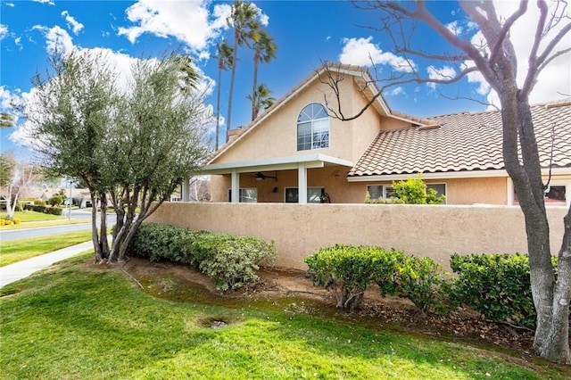 view of front of property with a front lawn, a fenced front yard, a tiled roof, and stucco siding