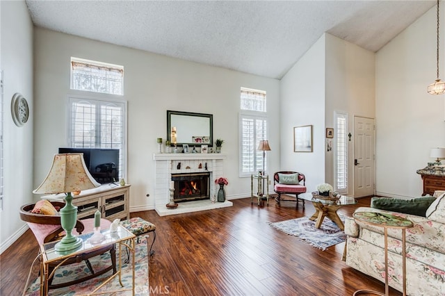 living room with dark wood finished floors, baseboards, a fireplace, and a textured ceiling
