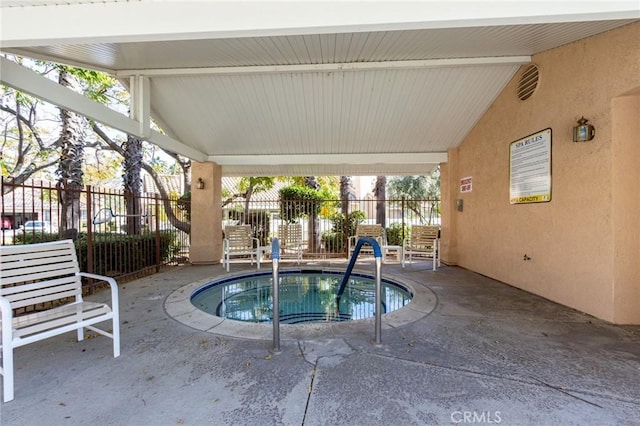 view of pool with a hot tub, fence, and a patio area