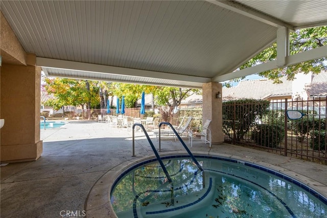view of swimming pool with a hot tub, fence, and a patio