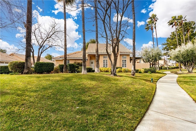 mediterranean / spanish-style home featuring stucco siding, a front lawn, and a tiled roof