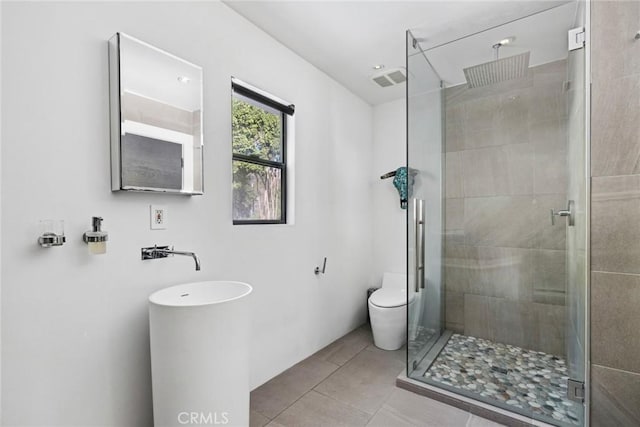 bathroom featuring toilet, tile patterned floors, and an enclosed shower