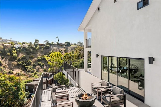 view of patio featuring a balcony and a fire pit