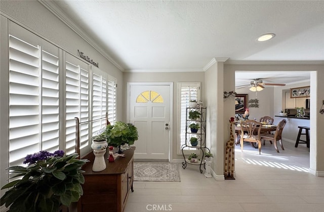 foyer entrance featuring ceiling fan, a textured ceiling, and crown molding