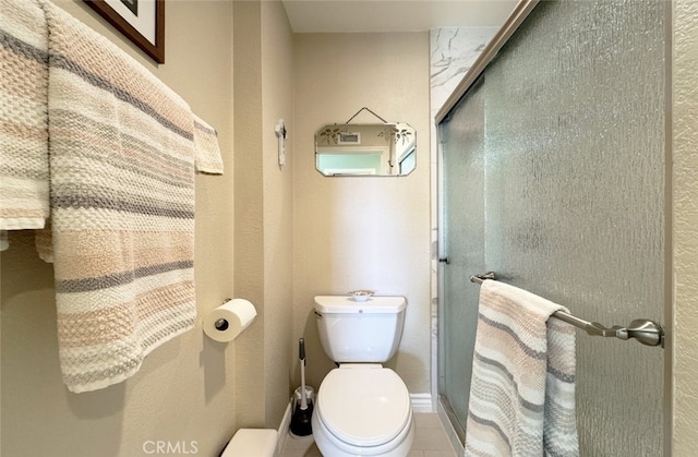 bathroom with a shower with shower door and toilet