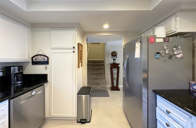 kitchen with dark stone countertops, stainless steel appliances, and white cabinetry