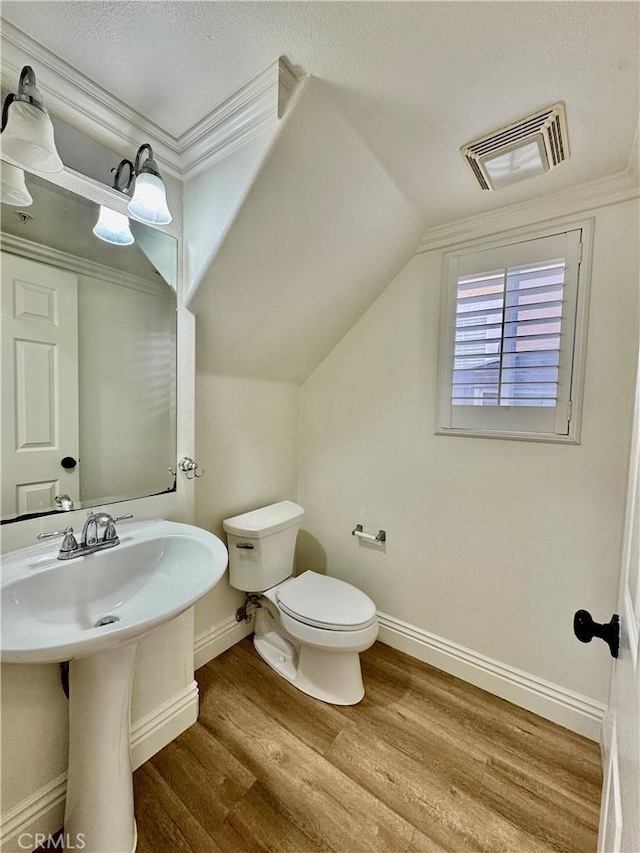 bathroom with hardwood / wood-style floors, toilet, a textured ceiling, and vaulted ceiling