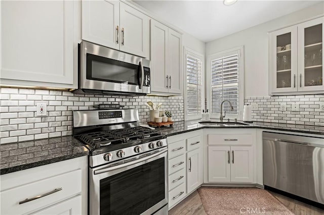 kitchen featuring dark stone countertops, sink, stainless steel appliances, and white cabinets