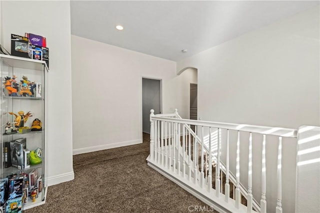 hall with dark colored carpet