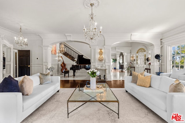 living room with a notable chandelier, crown molding, light hardwood / wood-style floors, and ornate columns