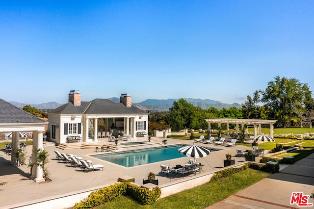 view of swimming pool featuring a pergola, a patio area, an outbuilding, and a mountain view