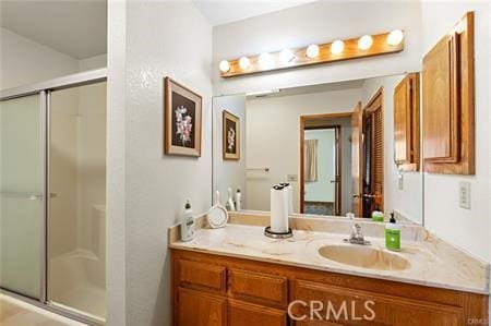 bathroom with a shower with door and vanity